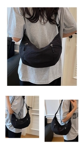 Dettaglio della tracolla regolabile e della spaziosa borsa a mezzaluna in nylon nero sul modello