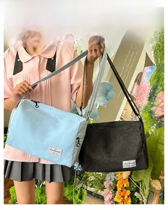 Detail of light blue and black canvas crossbody bags with adjustable shoulder straps