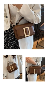 Detail of a brown PU leather crossbody bag with a large gold buckle and short handle
