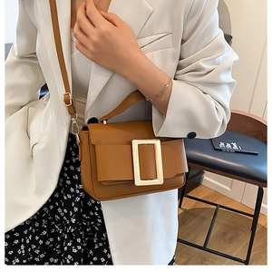 Detail view of brown caramel crossbody bag with large gold buckle and slim leather strap