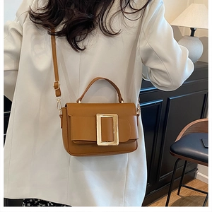 Side view of caramel leather crossbody bag worn by model in minimalist home setting
