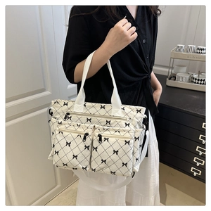 Detail of cream corduroy tote bag with bow pattern and functional front zipper pockets