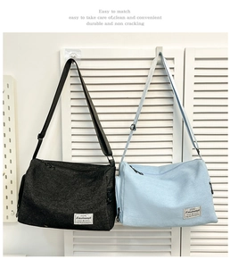 Detail of black and light blue textured canvas messenger bags with brand woven label