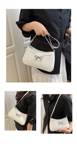 Detail view of white crocodile pattern shoulder bag with a silver metal bow buckle