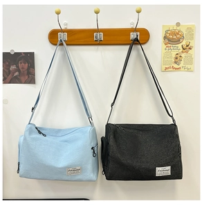 Détail de sacs bandoulière en toile bleu clair et noir avec sangles réglables et zips