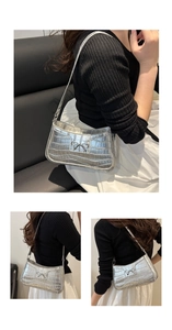 Detailed view of silver crocodile pattern bag with metallic bow and textured faux leather