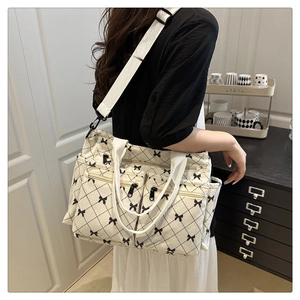 Detail view of large cream tote bag with black quilted bow pattern and multiple pockets