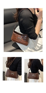 Detail of coffee brown crocodile pattern underarm bag with silver bow accent