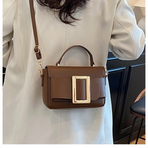 Close-up of brown leather bag with gold square buckle and adjustable shoulder strap