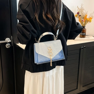 Blue PVC crossbody bag with silver metallic handle and gold logo shown on model's shoulder