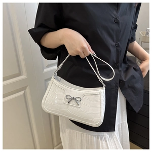 Macro shot of white crocodile embossed leather bag with silver metal bow detail