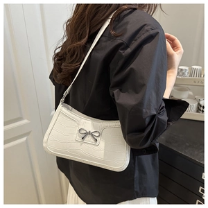 Close-up of white crocodile pattern shoulder bag featuring a silver metal bow buckle