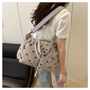 Detail of grey quilted tote bag with black bow print and multiple functional zipper pockets
