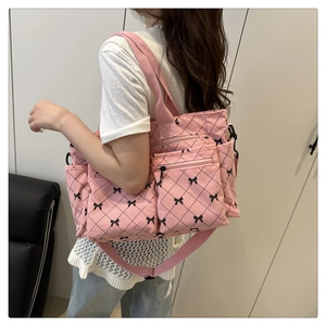 Pink corduroy tote bag detail with double front zipper pockets and black bow patterns