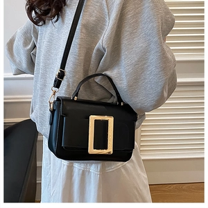 Detailed view of the large gold buckle and matte finish on this chic black crossbody bag