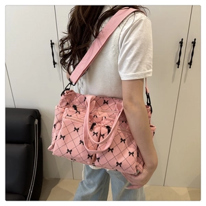 Detail of pink corduroy tote bag with black bow print and wide shoulder strap