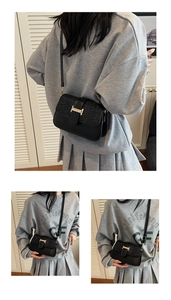 Detail of black crossbody bag with shimmering flap and golden H buckle on model