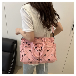 Detail of pink corduroy crossbody bag with quilted bow patterns and multi-pocket design