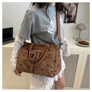 Detailed close-up of brown corduroy tote bag with black bow embroidery and double front pockets
