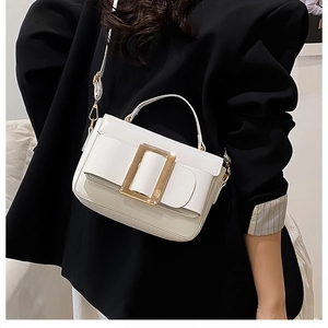 Detail of white leather crossbody bag with iconic gold buckle and adjustable strap