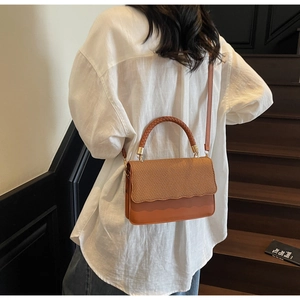 Close-up of caramel brown woven leather handbag with wave edge detail and top handle