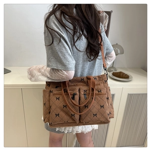 Brown corduroy quilted tote bag with black bow patterns and dual front pockets