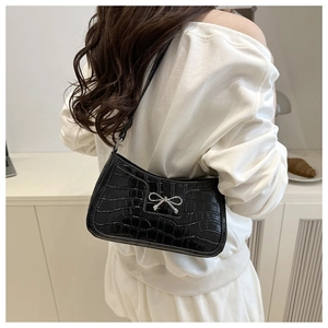 Close-up of black crocodile pattern shoulder bag featuring a silver metal bow buckle