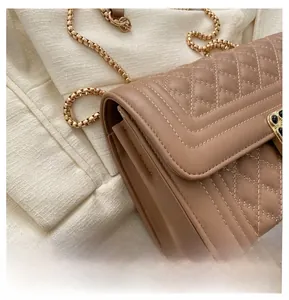 Detailed close-up of quilted pattern and gold chain strap on brown crossbody bag