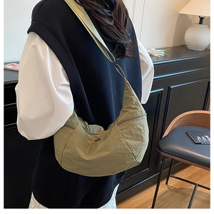 Foto lifestyle di una borsa a tracolla a mezzaluna in nylon verde indossata da un modello