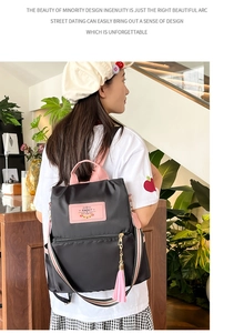 Detail of black and pink nylon backpack showing the Rabbit logo and cute fringe charm