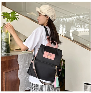 Detail of casual nylon backpack showing pink brand label and colorful tassel charm