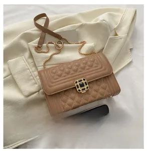 Detail of quilted brown crossbody bag with gold chain strap and black gemstone buckle