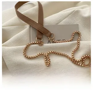 Detail of a brown quilted leather shoulder bag with gold chain strap and stitching