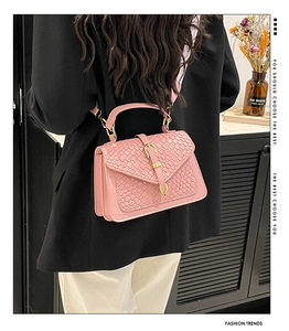 Pink woven texture crossbody bag with gold buckle shown on a model in a modern home setting