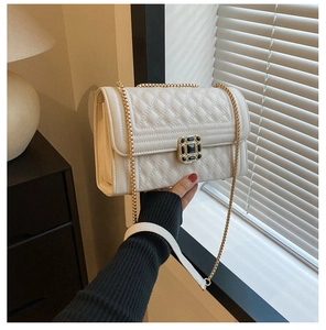 Detail of beige quilted leather bag with gold chain strap and black stone buckle