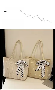 Détail de cabas en paille avec broderie marguerite et nœud en ruban à pois stylé