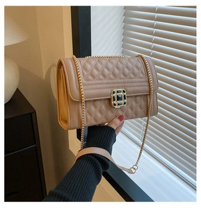 Detailed shot of quilted rhombus stitching and golden buckle on light brown handbag