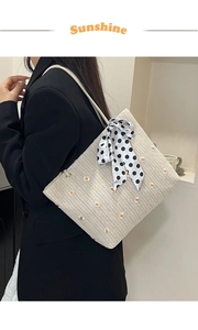 Détail d'un sac cabas en paille avec broderie marguerite et nœud à pois