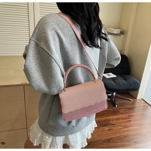 Close-up of dusty rose crossbody bag with woven texture flap and wave detail