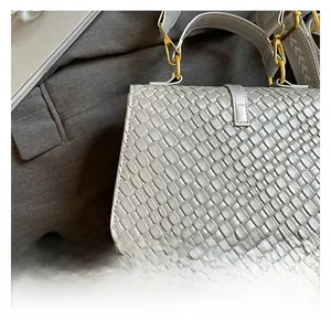 Detail of woven texture handbag with golden metal hardware and patterned strap