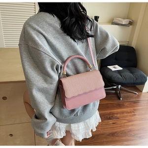 Detail of pink crossbody bag showing woven texture flap and circular braided handle