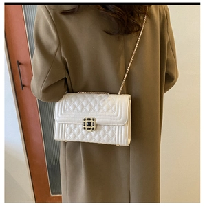 Detail of off-white quilted shoulder bag with gold chain strap and square turn-lock