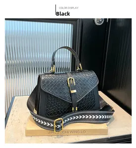 Detail of black woven texture handbag with gold buckle and geometric wide strap