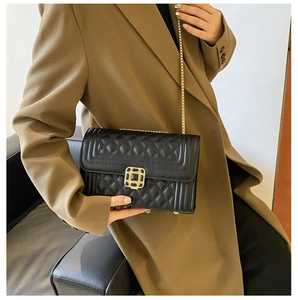 Detail of black quilted leather shoulder bag with vintage gold clasp and chain strap