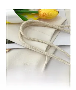 Close-up of thick woven handles and twill texture on a beige tote bag with floral accents