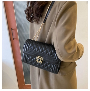 Detail of black quilted leather shoulder bag with gold chain and square metal lock