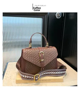 Detail of coffee brown woven textured handbag with golden buckle and patterned strap