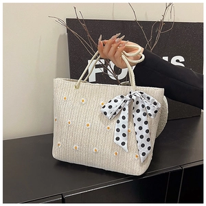 Détail du sac cabas en paille beige avec broderie marguerite et nœud en soie à pois