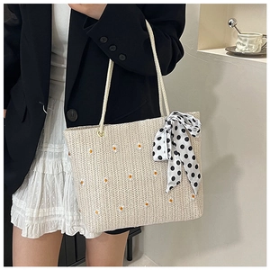 Détail de broderie marguerite et nœud à pois sur le grand sac cabas en paille beige