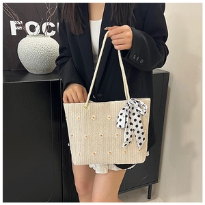 Détail du sac cabas en paille avec broderie marguerite et foulard en soie à pois noir